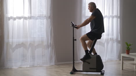 Entrenamiento-Deportivo-En-Bicicleta-Estacionaria,-Un-Hombre-De-Mediana-Edad-Está-Haciendo-Girar-Los-Pedales,-Ejercicio-Para-La-Salud-Del-Sistema-Cardiovascular-Y-Mantenerse-En-Forma